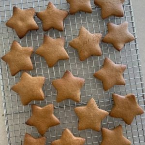 Sourdough gingerbread cookies in the shape of stars, cooling on a rack after just being baked.