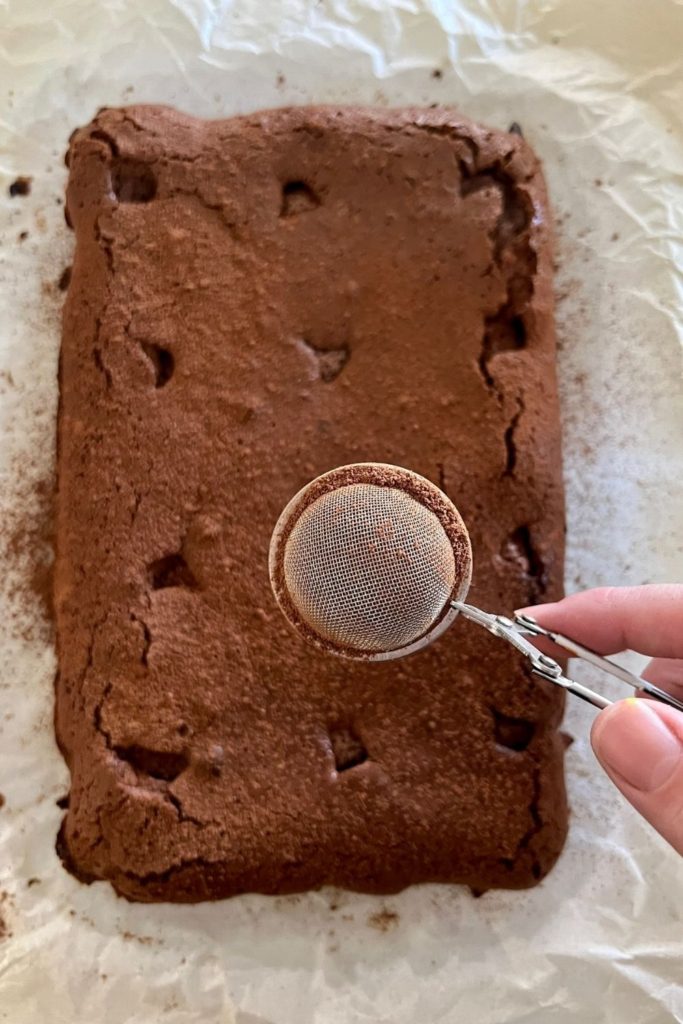 Dusting sourdough brownies with cocoa after baking.