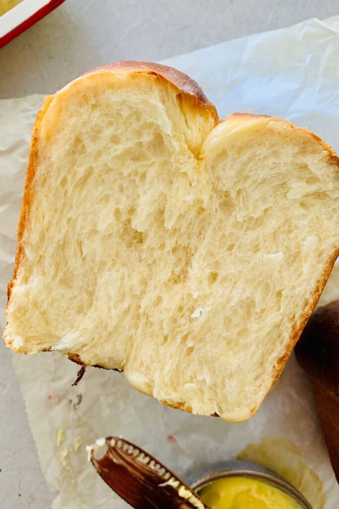 Loaf of sourdough brioche bread that has been cut through the middle to show the light, fluffy crumb.
