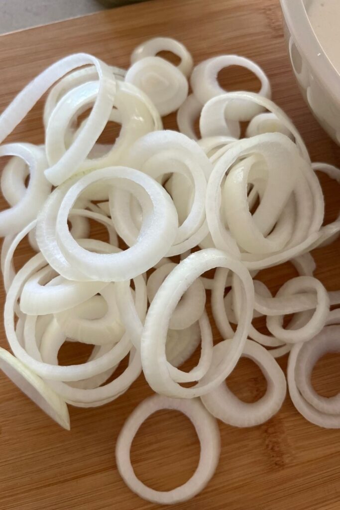 A brown onion cut into slices ready to be dipped into sourdough batter.