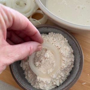 Dipping onion rings into AP flour.
