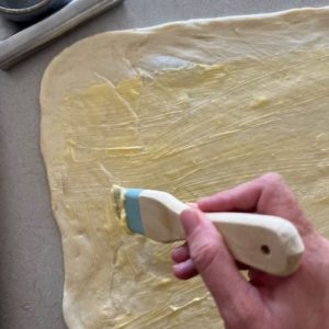 brush the dough with butter using a pastry brush leaving a gap at the top