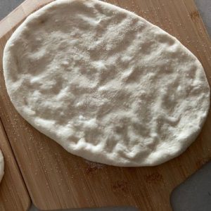 Fougasse dough shaped into an oval and placed onto a pizza peel with semolina