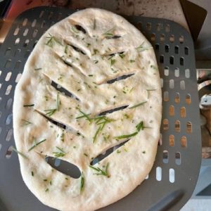 Putting sourdough fougasse into a hot pizza oven using a perforated pizza peel