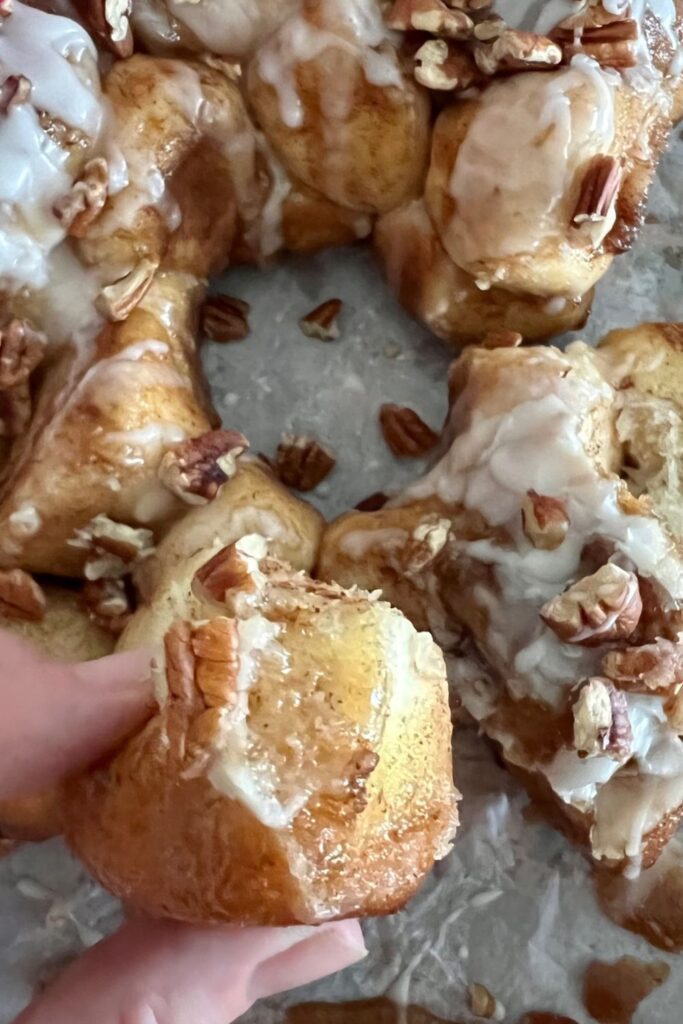Photo shows a hand tearing a piece of sourdough discard monkey bread