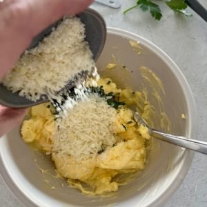 Adding parmesan cheese to butter, salt and parsley