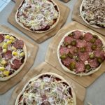 Best pizza toppings for homemade pizza - this photo shows 6 homemade pizzas all with different toppings.