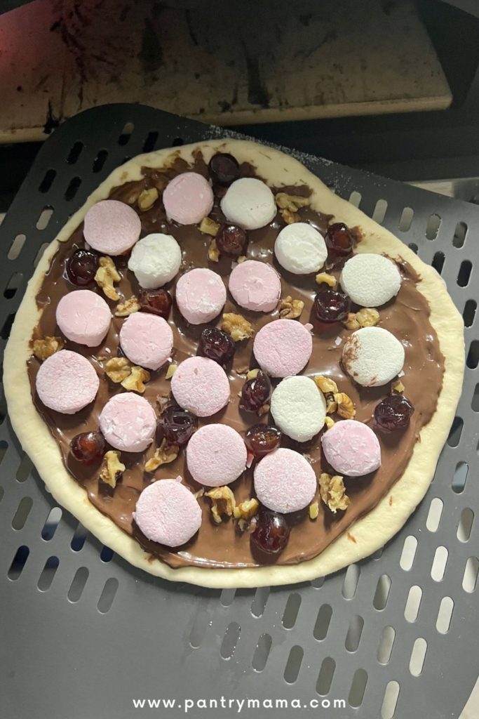 Best sweet pizza topping - pizza with nutella, marshmallows, cherries and walnuts about to be baked in a gas pizza oven.