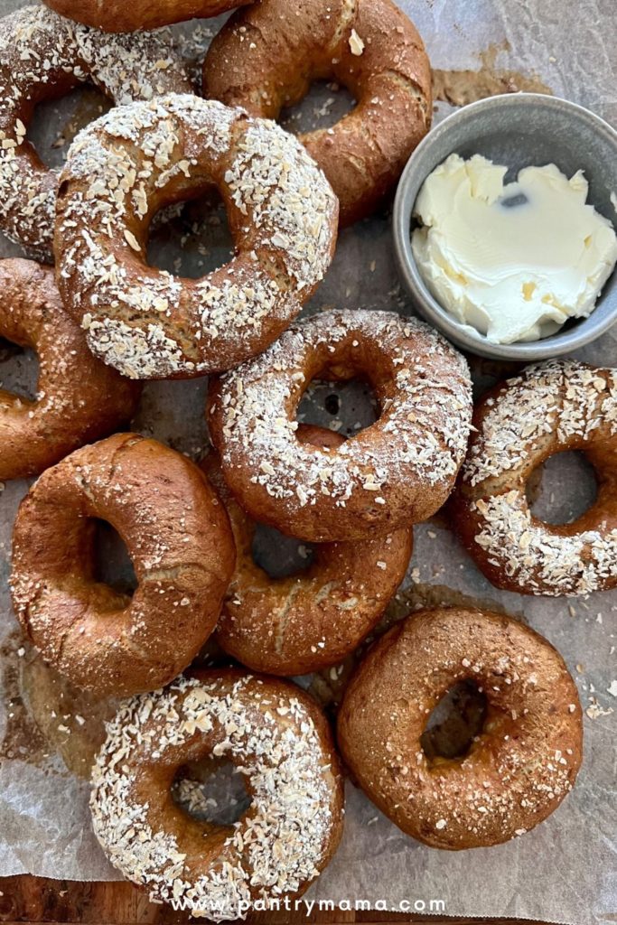 A pile of sourdough rye bagels served with a dish of cream cheese.