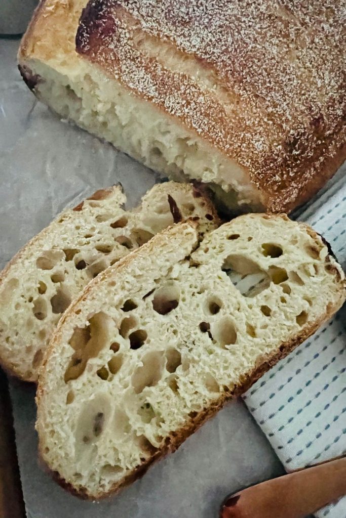 A very under fermented sourdough bread sliced so you can see the big holes surrounded by a tight crumb.