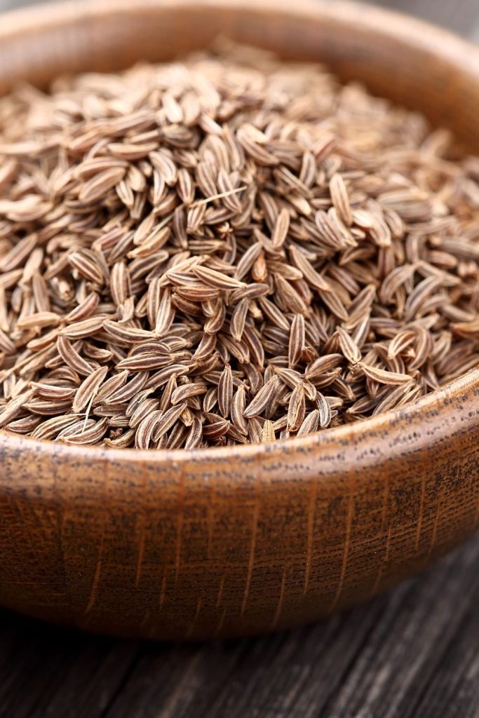 Caraway seeds sitting in a small brown bowl.