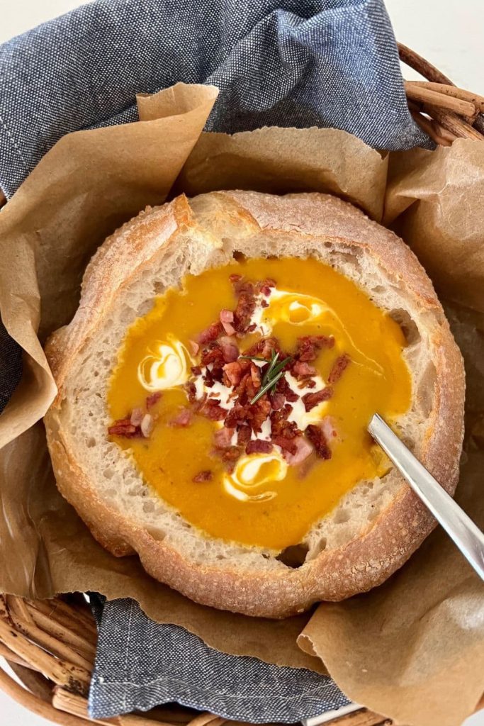 Sourdough Bread Bowl filled with pumpkin soup that has been topped with sour cream and bacon.